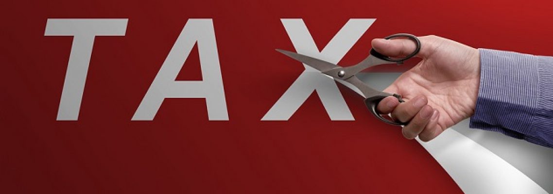 Business hand with scissors cutting Tax word on red paper
